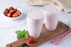 Yogurt , buttermilk or kefir with strawberry. Yogurt in glass on light background. Probiotic cold fermented dairy drink. Gut health, fermented products, healthy gut flora concept