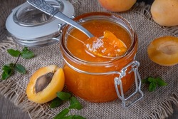 Jam from apricots in a glass jar on an old wooden table