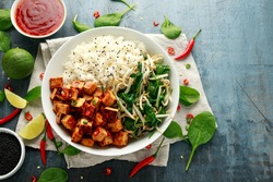 Fried tofu in sweet chilli glaze served with rice, steamed spinach and beansprouts in white bowl. Vegetable healthy food