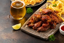 Buffalo chicken wings with beer, french fries on wooden board. fast food