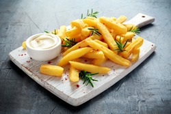 Homemade Baked Potato Fries with Mayonnaise and rosemary on white wooden board