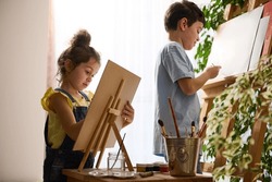 Beautiful smart children, preschool girl schoolboy enjoying art class, drawing, painting images on canvas with oil and watercolor paints. Creativity, education, art, kidsnentertainment, hobby concept