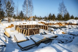 Wooden piled formwork beams under the snow. Equipment for concrete work at a construction site. Formwork