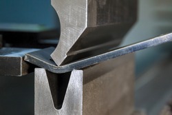 Bending sheet metal with a hydraulic machine at the factory. Closeup.