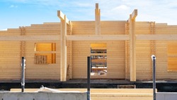Modern wooden house made of profiled laminated timber. 
The wall of a residential building from glued laminated timber or lamstock close-up. Construction of a fence with a concrete base.