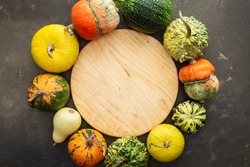 Decorative and edible pumpkins on a green background, cutting board in the middle of the background, top view, autumn background, copy space