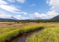 Scenic wide angle view of mountains and puffy white cloud sky in Sisters, Oregon, on a beautiful sunny summer day.