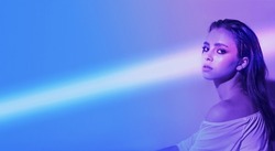 the laser beam is directed at a young girl, laser hair removal and smooth skin, a beautiful fashionable female on a purple blue background