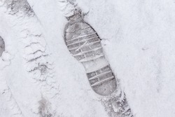 on fresh snow, an imprint of the soles of winter shoes with a transverse pattern providing safe walks on snow-covered and icy surfaces, selective focus