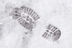 on the freshly fallen snow, the imprint of the sole of winter shoes with a large pattern that ensures safe movement on snow-covered and icy sidewalks, selective focus