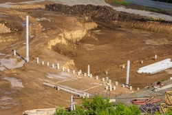 construction site with a foundation pit of complex shape with several bottom levels, several piles of piles are installed at the bottom of the pit, selective focus