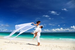 Bride and groom having fun on white sandy tropical beach. Beach wedding concept