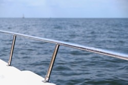 View on the water and in the foreground a boat railing in silver