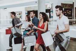 Company of Friends Shopping in Mall with Packages. Shopping Concept. Girl in Red Dress. Woman in White Shirt. Black Friday Concept. Exited Young People. Modern Market. Packs in Hands.