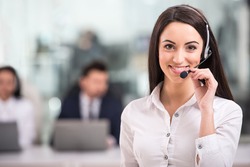 Portrait of happy smiling female customer support phone operator at workplace.