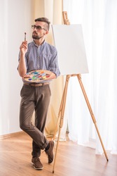 Portrait of highly gifted painter is holding brush in his hand is going to paint a picture.