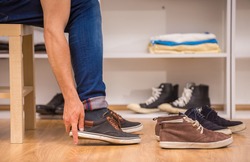 Close-up of man putting on shoes in dressing room.