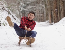 Man riding a sleigh with frightened and anxious face, fear of falling off the sledge - it's getting to fast