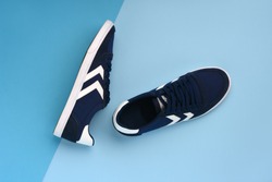 A pair of navy blue sneakers lying on a dark and light blue background. Minimal photo