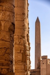 Ancient columns and obelisk in the background at Temple of Karnak in Luxor, Egypt.