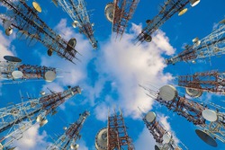 Mobile phone communication antenna tower with cloud on center blue sky, Telecommunication tower perspective.