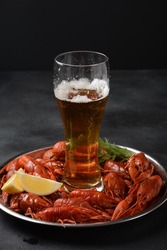 Red boiled crawfishes on table in rustic style. Asian Chinese Food Spicy Crayfish on an iron plate with a mug of beer. 