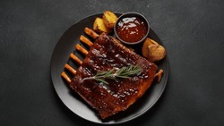 Closeup of pork ribs grilled with BBQ sauce and caramelized in honey. 
Grilled pork ribs with spices on a stone background 