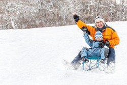 Young father and son sledding at winter time