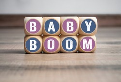 Wall made of cubes and dice with word baby boom on wooden background