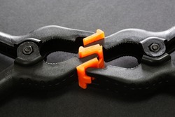 Selective focus of plastic clamps holding each other on black isolated background. Abstract concept of love, romance, passion, attachment, hugging.
