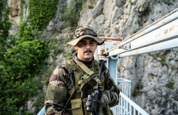 Special force military soldier portrait smiling in battle zone or military practice wearing combat uniform and hat on the bridge in nature guard patrol