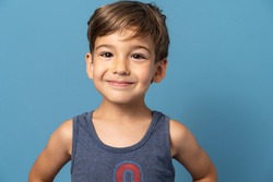 Front view of small caucasian boy four years old standing in front of blue background studio shot child smiling happiness and joy concept