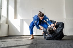 Two brazilian jiu jitsu BJJ athletes training at the academy martial arts ground fighting sparring wear kimono gi sport uniform on the tatami mats sports jiujitsu and self-defense concept copy space