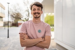 One young caucasian man with brown hair and mustaches wearing t-shirt looking to the camera modern happy adult male smile confident portrait in front of white wall copy space waist up