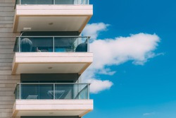 Balconies and blue sky with clouds. Part of a residential building in Israel. Modern apartment buildings on a sunny day. Architectural details. Modern residential white building with balcony 