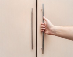 male hand are open the cupboard doors, light wood.