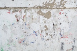 Grunge background texture. The background image is a white shabby wall with traces of multicolored inscriptions and graffitti. Surface in places flaked, sprinkled and there is visible brown plaster.