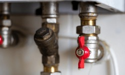 Hidden water taps for connecting a gas boiler on a tiled wall. Plumbing connections for a domestic double-circuit gas boiler. Pipes of the heating system. Installing a gas boiler with red taps