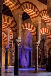 Arches and columns inside the cathedral mosque of Córdoba, with an entrance of natural light.