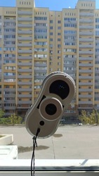 Vacuum cleaner robot washing glass window. Blue sky and building background. Robot assistant at home for cleaning windows.