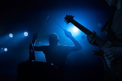 Band performing live during concert, gig. Guitarist and drummer silhouettes
