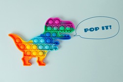New silcone toy pop it in shape of dinosaur on the blue background,with drawing growls.New sensory antistress toy for children and adult.Trendy rainbow coloring.
