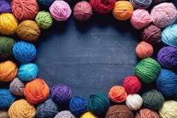 Colorful balls of wool on wooden table. Variety of yarn balls, view from above.