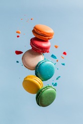 Different types of macaroons in motion falling on light 
blue background. Sweet and colorful french macaroons falling or flying in motion. 