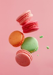 Different types of macaroons in motion falling on pink background. Sweet and colourful french macaroons falling or flying in motion. 