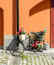 a bicycle decorated with flowers by the house wall