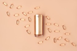 Beautiful composition of gold mockup cosmetic bottle and vitamin capsules on pastel background. Natural cosmetics concept in trendy colors. Creative trendy cosmetics flat lay with copy space.