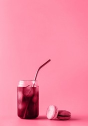 Glass of iced coffee in tall glass with cream and macaroons toned in trendy magenta color of year 2023. Food concept. Copy space. Close-up.