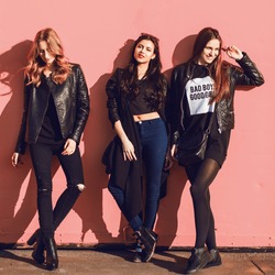 Fashion lifestyle  photo of three  stylish hipster friends in black spring outfit posing against pink urban  wall.