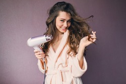  Close up portrait of beautiful young woman in pink bathrobe  drying hairstyle. Cute young  lady smiling .